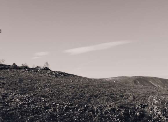 White cross on a green hill symbolizing the parables of Jesus