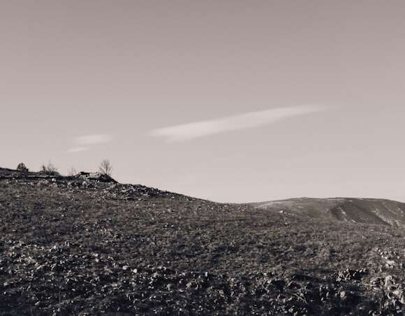 White cross on a green hill symbolizing the parables of Jesus