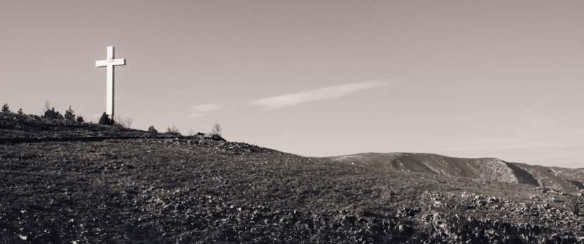 White cross on a green hill symbolizing the parables of Jesus